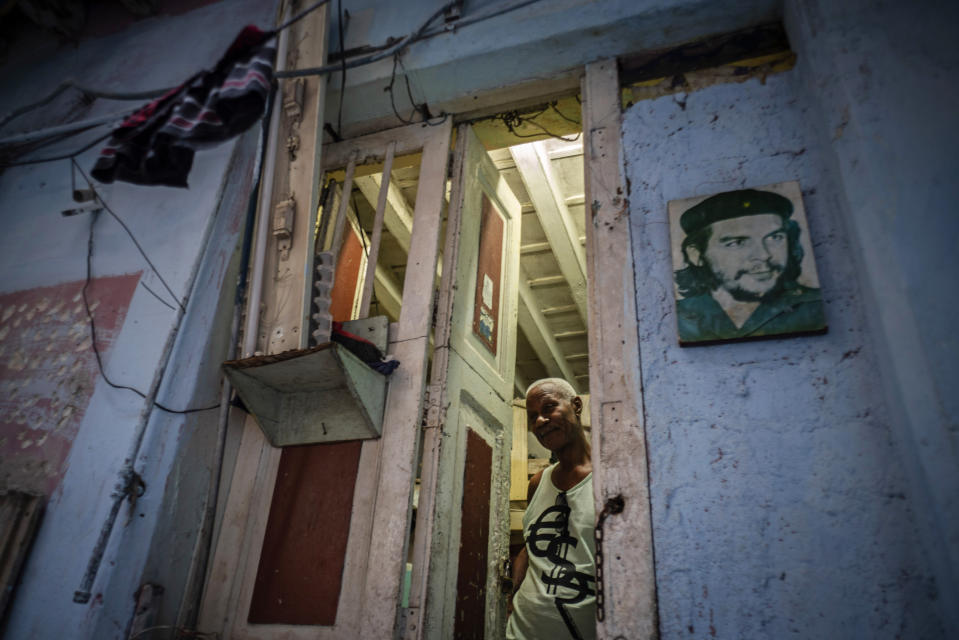 In this Nov. 10, 2019 photo, Lorenzo Ballester poses at the door of his house, decorated with a photo of revolutionary hero Ernesto "Che" Guevara, in Havana, Cuba. The city of Havana will celebrate its 500th anniversary on Nov. 16. (AP Photo/Ramon Espinosa)