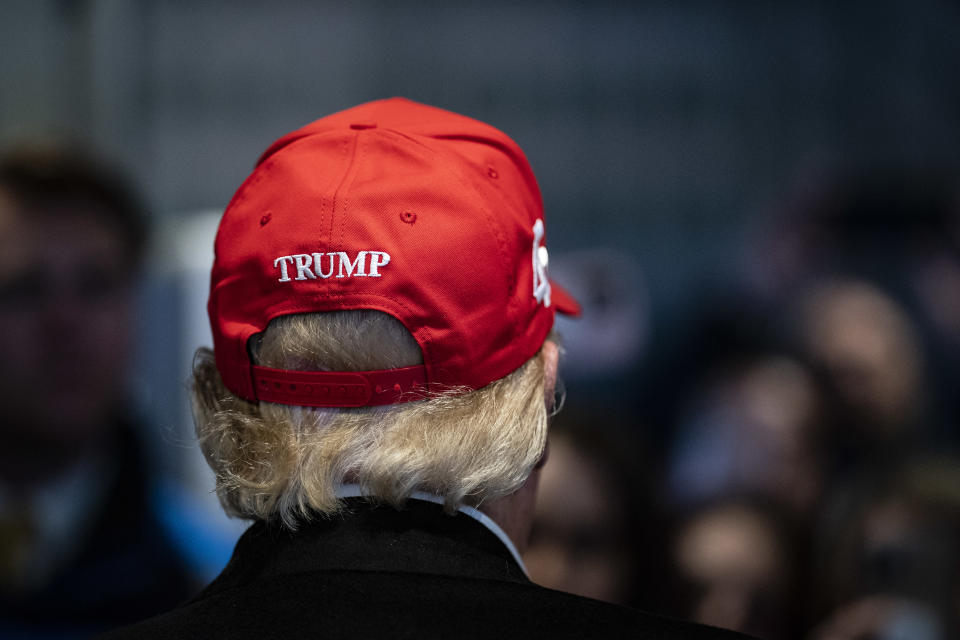 Former President Donald Trump is seen from behind. The cap he is wearing has his last name stitched on the back.
