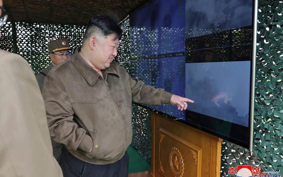 Kim Jong-un points at a screen, with a senior military officer behind him