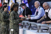 President Joe Biden and chef Robert Irvine, right, help serve a "friendsgiving" meal to service members and their relatives at the Norfolk Naval Station on Sunday, Nov. 19, 2023, in Norfolk, Va. (AP Photo/Manuel Balce Ceneta)