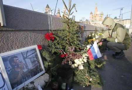 A man lights a candle at the site, where Russian opposition politician Boris Nemtsov was killed, on the Great Moskvoretsky Bridge, with the Kremlin towers (L) and St. Basil's Cathedral seen in the background, in central Moscow, Russia, December 29, 2015. REUTERS/Maxim Zmeyev/Files