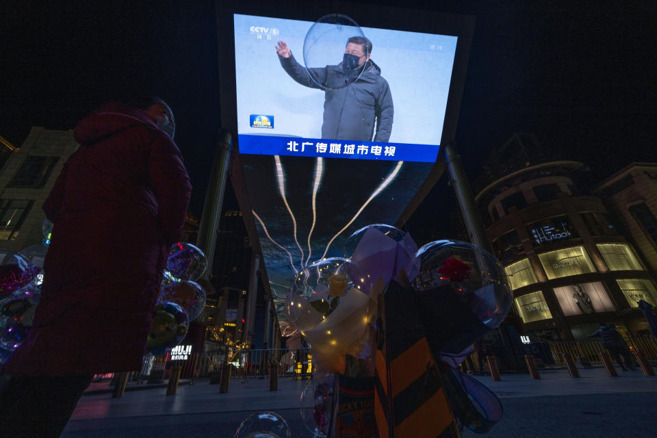 A balloon floats past a screen showing a news report on the Chinese President Xi Jinping attending the opening ceremony of the 2022 Winter Olympics in Beijing, China, Saturday, Feb. 5, 2022. (AP Photo/Ng Han Guan)