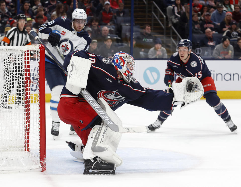 Columbus Blue Jackets goalie Joonas Korpisalo, center, makes a stop in front of Winnipeg Jets forward Pierre-Luc Dubois, left, and Blue Jackets defenseman Gavin Bayreuther during the first period of an NHL hockey game in Columbus, Ohio, Thursday, Feb. 16, 2023. (AP Photo/Paul Vernon)