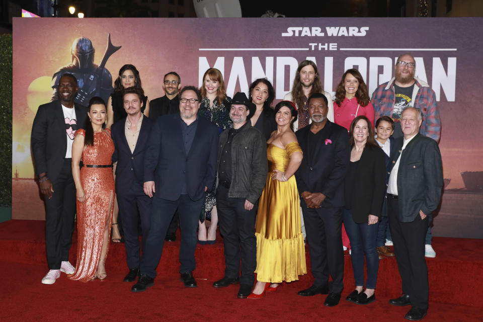 Rick Famuyiwa, from left, Ming-Na Wen, Julia Jones, Pedro Pascal, Omid Abtahi, Jon Favreau, Bryce Dallas Howard, Dave Filoni, Deborah Chow, Gina Carano, Ludwig Goransson, Carl Wethers,Emily Swallow, Kathleen Kennedy, Aidan Bertola, Brian Posehn, and Werner Herzog attend the LA Premiere of "The Mandalorian" at the El Capitan theatre on Wednesday November 13, 2019 in Los Angeles. (Photo by Mark Von Holden/Invision/AP)