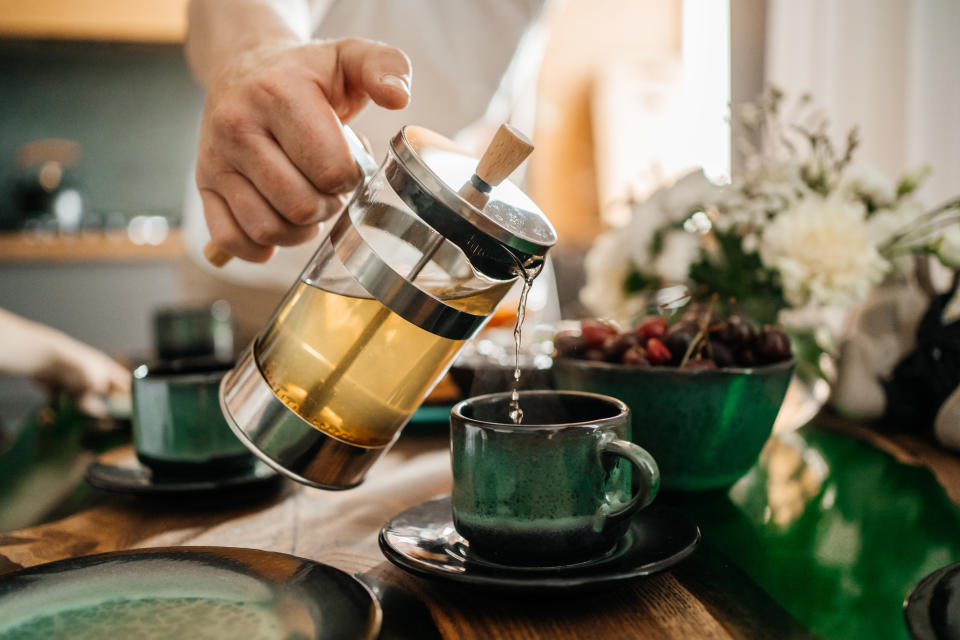 green tea pours into a cup, glass teapot