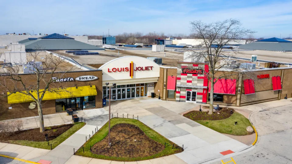 Joliet, IL, USA – April 8, 2019: A drone / aerial shot of a Louis Joliet Mall entrance with a Panera Bread and TGI Fridays on either side.