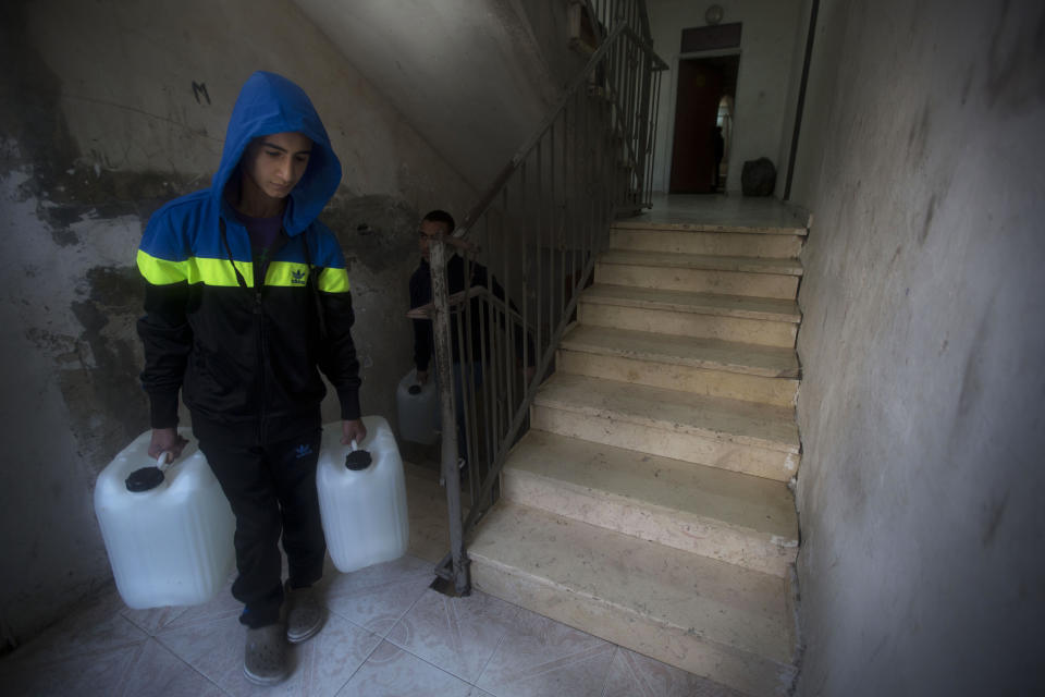 In this April 3, 2014 photo, a Palestinian carries water tanks to his house in Shuafat, east Jerusalem. Tens of thousands of Palestinians in east Jerusalem have been without water for more than a month, victims of a decrepit and overwhelmed infrastructure and caught in a legal no-man’s land. Their district is technically part of Jerusalem municipality, but on the other side of the massive Israeli-built West Bank separation barrier, so Israeli services there are sparse yet Palestinian officials are barred for operating. With the scorching summer approaching, residents are growing increasingly desperate. (AP Photo/Sebastian Scheiner)