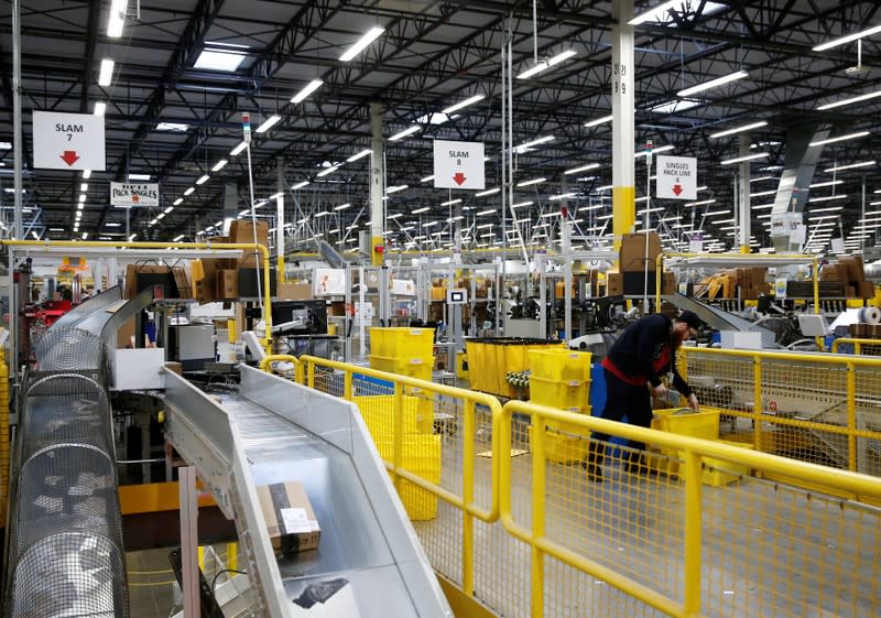 An employee monitors packages at automated scanning and labeling conveyor lines at the Amazon fulfillment center in Kent