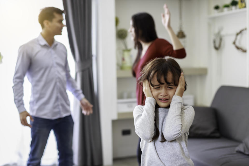 Crying girl with his fighting parents in the background, Sad gril while parents quarreling in the living room