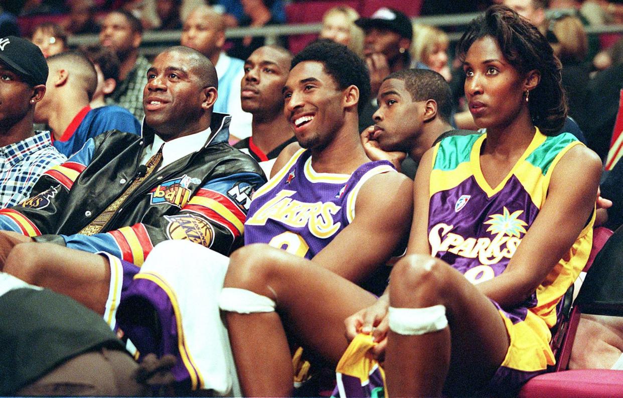 The 2-ball team with Los Angeles Lakers' Kobe Bryant (C) and Lisa Leslie (R) sit on the bench with their coach Magic Johnson (L), the three-time Lakers' Most Valuable Player, while attending the inaugural Nestle Crunch All-Star 2-ball competition, which was held as part of the 1998 All-Star Weekend in New York on Feb. 7, 1998. The Los Angeles team finished fifth in the eight team competition.