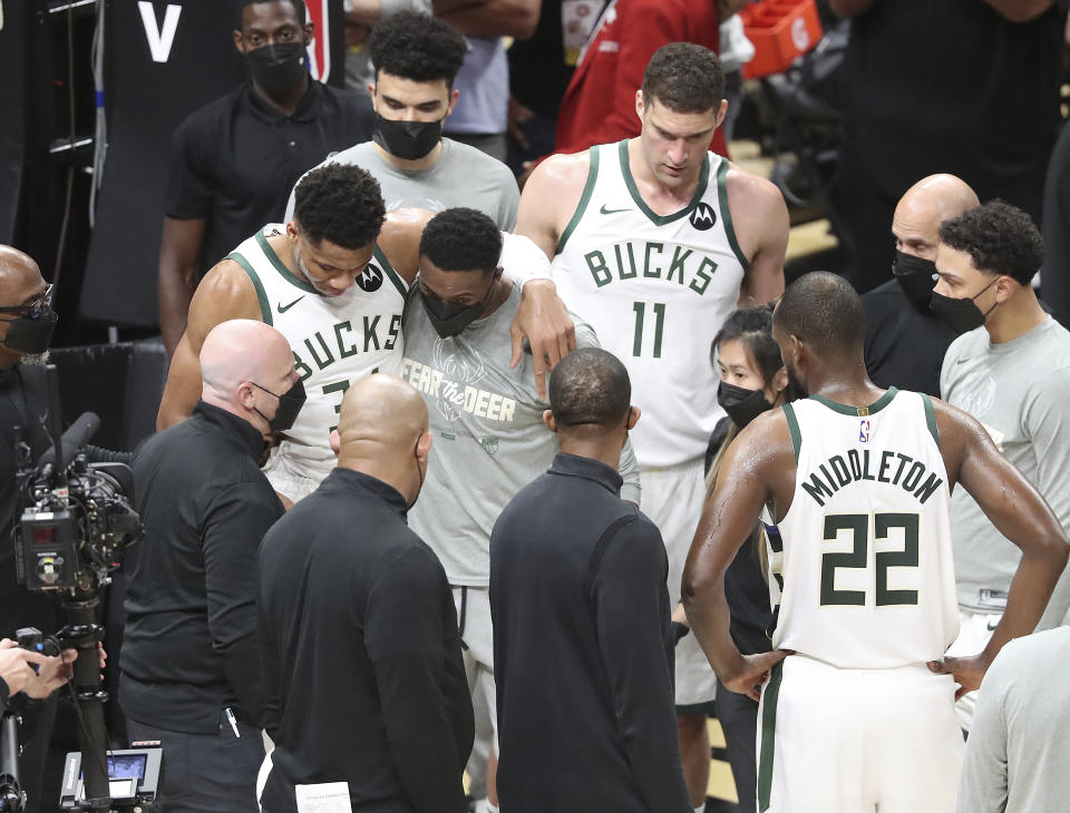 Milwaukee Bucks forward Giannis Antetokounmpo is helped up by his brother Thanasis Antetokounmpo (right), who also plays for the team, after he hyperextended his left knee on this play hitting the floor after rising to challenge a slam by Atlanta Hawks center Clint Capela on a lob pass by Lou Williams with 7:14 left in the third quarter of game 4 in the NBA Eastern Conference Finals on Tuesday, June 29, 2021, in Atlanta. (Curtis Compton/Atlanta Journal-Constitution via AP)