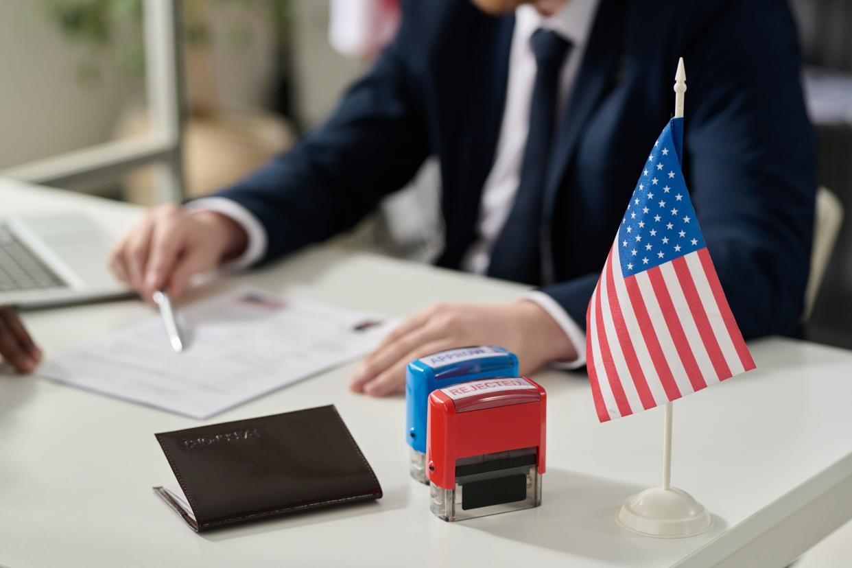 Man going through immigration application at US immigration office with American flag.