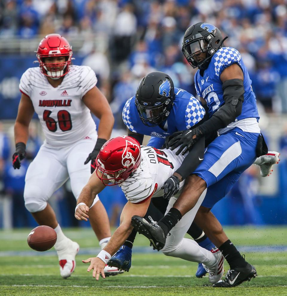 Kentucky linebacker Jordan Wright (15) and linebacker J.J. Weaver (13) bulldoze their way past Louisville quarterback Brock Domann (19) after sacking him and knocking the ball loose in the first half in Saturday's Governors Cup college football game. Nov. 26, 2022.  