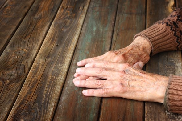 close up of elderly male hands on wooden table