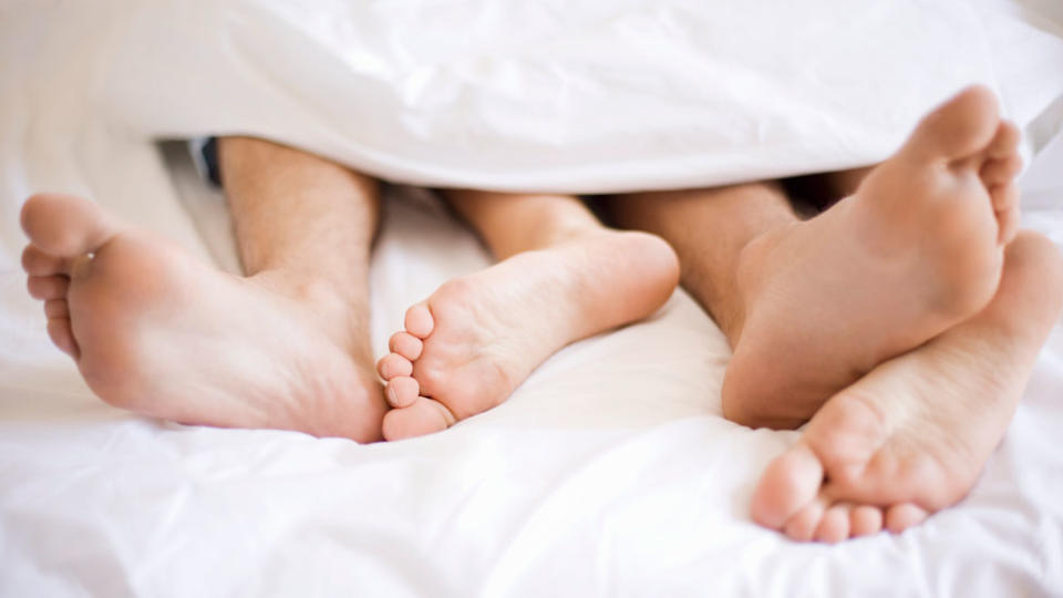 Pies de un hombre y una mujer en la cama