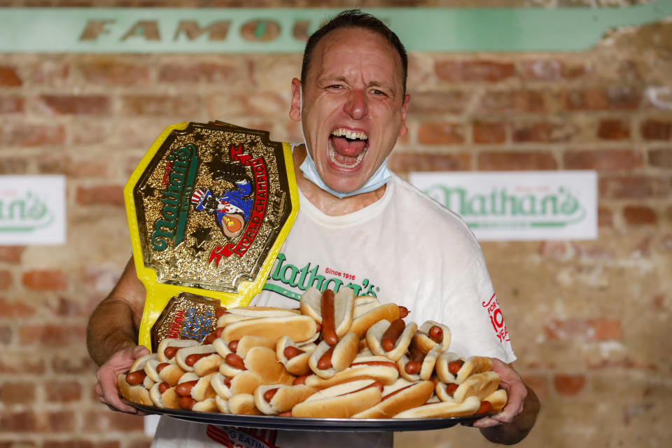 El concursante Joey Chestnut celebra después de fijar un nuevo récord mundial, con 75 hot dogs, para ganar la división masculina del concurso de comer hot dogs Nathan's Famous, el sábado 4 de julio de 2020, en el distrito de Brooklyn, en la ciudad de Nueva York. (AP Foto/John Minchillo)