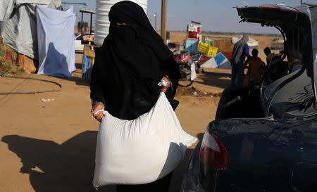 A Palestinian woman carrying a bag of flour arrives to bake bread at a tent city protest where Palestinians demand the right to return to their homeland at the Israel-Gaza border, in the southern Gaza Strip April 11, 2018. REUTERS/Samar Abo Elouf