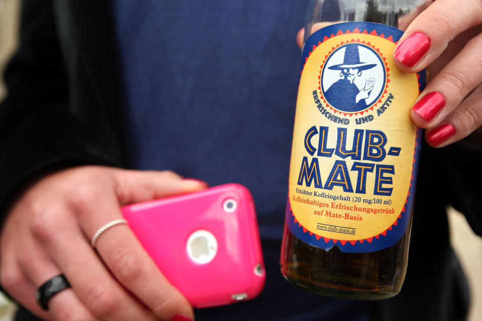 BERLIN, GERMANY - JULY 21: A visitor shows her bottle of Club-Mate carbonated yerba mate drink during the second annual Hipster Olympics on July 21, 2012 in Berlin, Germany. With events such as the "Horn-Rimmed Glasses Throw," "Skinny Jeans Tug-O-War," "Vinyl Record Spinning Contest" and "Cloth Tote Sack Race," the Hipster Olympics both mocks and celebrates the Hipster subculture, which some critics claim could never be accurately defined and others that it never existed in the first place. The imprecise nature of determining what makes one a member means that the symptomatic elements of adherants to the group vary in each country, but the archetype of the version in Berlin, one of the more popular locations for those following its lifestyle, along with London and Brooklyn, includes a penchant for canvas tote bags, the carbonated yerba mate drink Club Mate, analogue film cameras, asymmetrical haircuts, 80s neon fashion, and, allegedly, a heavy dose of irony. To some in Berlin, members of the hipster "movement" have replaced a former unwanted identity in gentrifying neighborhoods, the Yuppie, for targets of criticism, as landlords raise rents in the areas to which they relocate, particularly the up-and-coming neighborhood of Neukoelln. (Photo by Adam Berry/Getty Images)