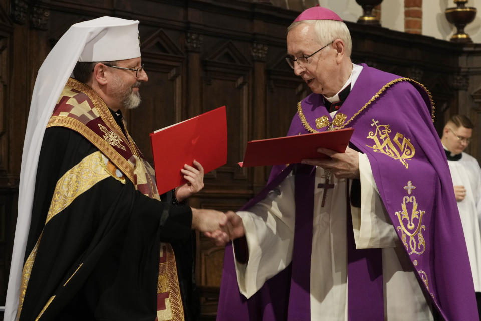 Archbishop Sviatoslav Shevchuk of the Ukrainian Greek Catholic Church, left, and the head of Poland's Roman Catholic Church, Archbishop Stanislaw Gadecki, right, exchange forgiveness and reconciliation notes during a joint religious service held as part of observances honoring some 100,000 Poles murdered by Ukrainian nationalists in 1943-44, at St. John's cathedral in Warsaw, Poland, on Friday, July 7, 2023. (AP Photo/Czarek Sokolowski)