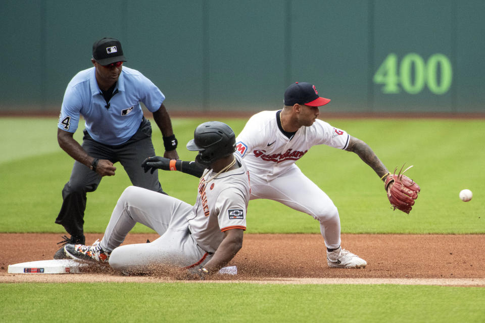 San Francisco Giants' Jorge Soler slides safely into second base for a double as Cleveland Guardians' Brayan Rocchio waits for the throw as umpire Alan Porter watches the play during the first inning of a baseball game in Cleveland, Saturday, July 6, 2024. (AP Photo/Phil Long)