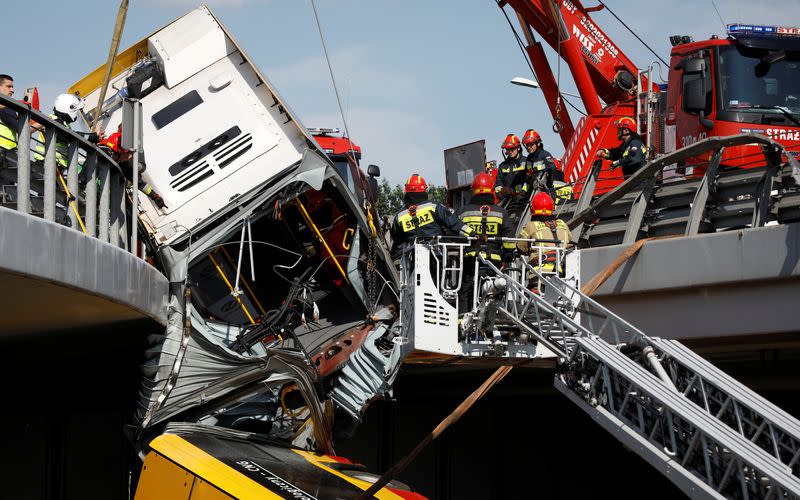 Emergency personnel work at the site of a crash after a city bus fell off a motorway bridge in Warsaw
