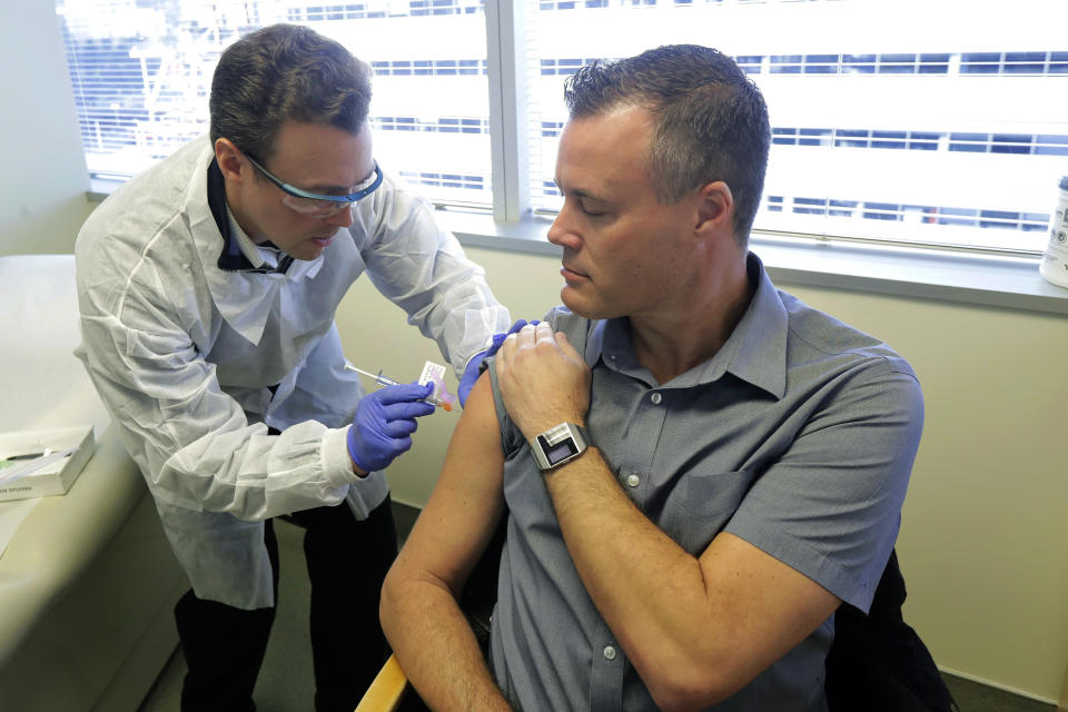 Pharmacist Michael Witte, left, gives Neal Browning, right, a shot in the first-stage safety study clinical trial of a potential vaccine for COVID-19, the disease caused by the new coronavirus Monday, March 16, 2020, at the Kaiser Permanente Washington Health Research Institute in Seattle. Browning is the second patient to receive the shot in the study. (AP Photo/Ted S. Warren)