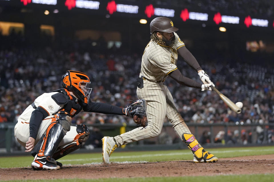 San Diego Padres' Fernando Tatis Jr. hits a single in front of San Francisco Giants catcher Buster Posey during the sixth inning of a baseball game in San Francisco, Wednesday, Sept. 15, 2021. (AP Photo/Jeff Chiu)