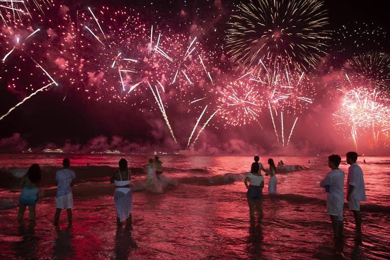 Turistas disfrutan de los fuegos artificiales en la playa: una clásica postal de Año Nuevo en Río de Janeiro.