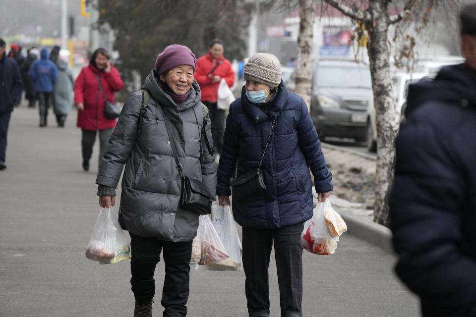FILE - Two local women smile talking to each other as they walk through a street in Almaty, Kazakhstan, Tuesday, Jan. 11, 2022. The price of gas soared to 120 tenge ($0.27) per liter, a significant increase in the country where, according to Tokayev's own admission, half the population earns no more than 50,000 tenge ($114) a month. (AP Photo/Sergei Grits, File)