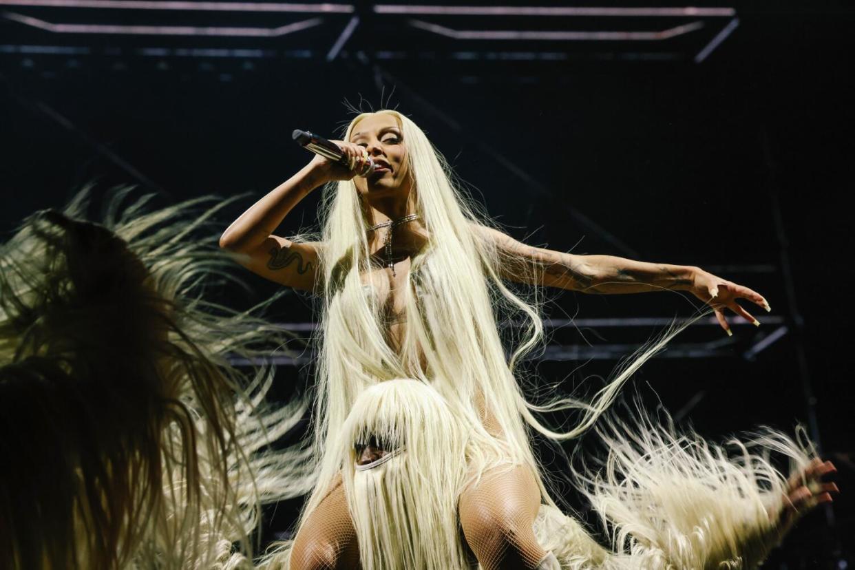 Doja Cat sits on the shoulders of a person in a hairy costume.