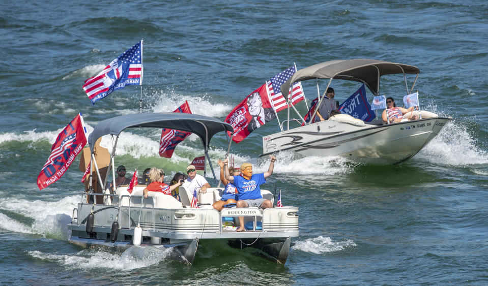 FILE-This Saturday, Sept. 5, 2020 file photo shows a Trump masked boat rider waving to those on the Hwy 421 bridge during the South Holston Trump Boat Parade in Bristol, Tenn. Grassroots supporters for President Donald Trump have organized hundreds of boat, car and tractor parades across the nation to generate enthusiasm for his re-election campaign. Campaign strategists and analysts say the parades are a reflection of the president's populist appeal, but they have varying thoughts on whether they will impact the outcome. (Earl Neikirk/Bristol Herald Courier via AP, File)