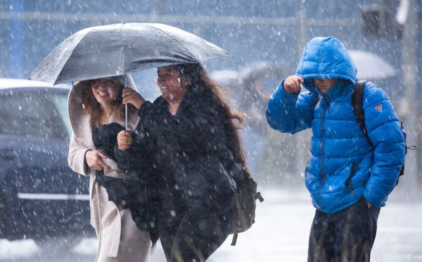 LOS ANGELES, CA - MARCH 21: Pedestrians shield themselves from the rain in Van Nuys during a wet Tuesday afternoon. (Myung J. Chun / Los Angeles Times)