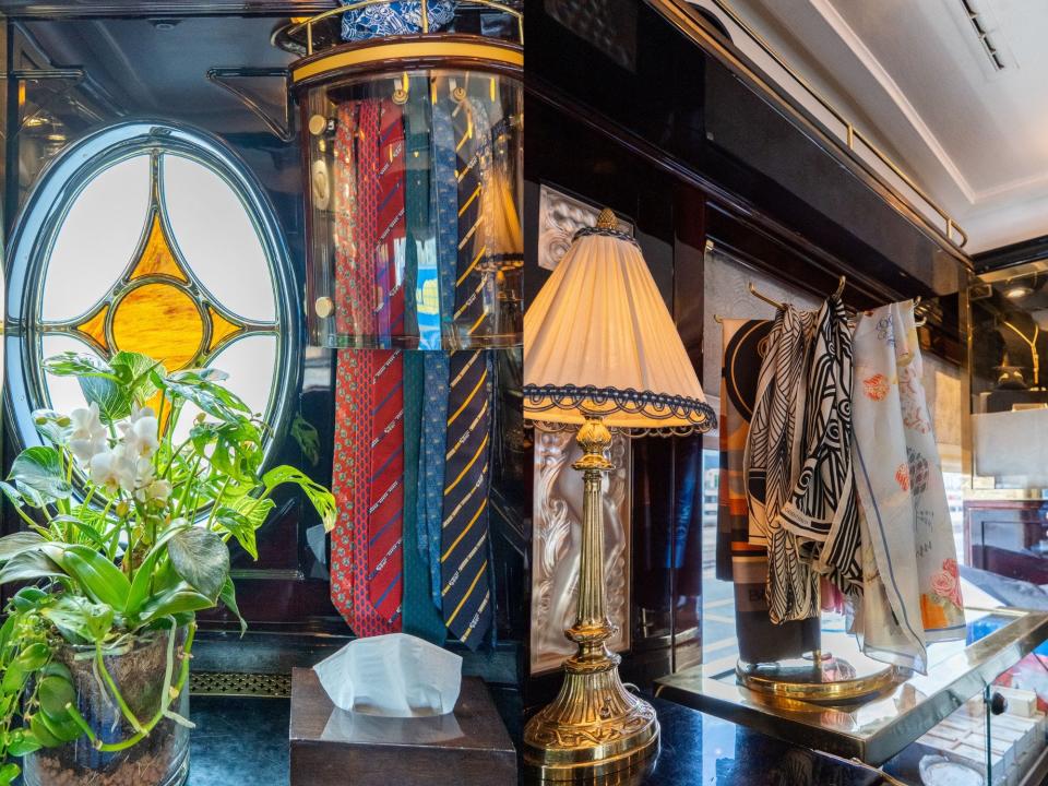 Side-by-side photos of a train boutique with dark walls, a gold lamp, and ties and scarves on display