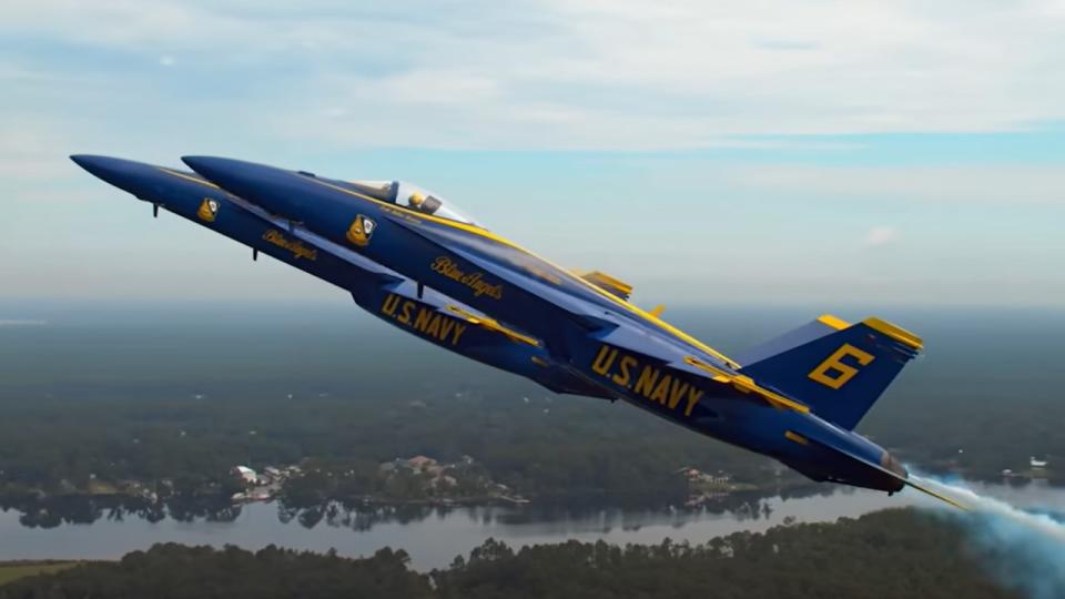 Two Blue Angels jets flying upward side by side