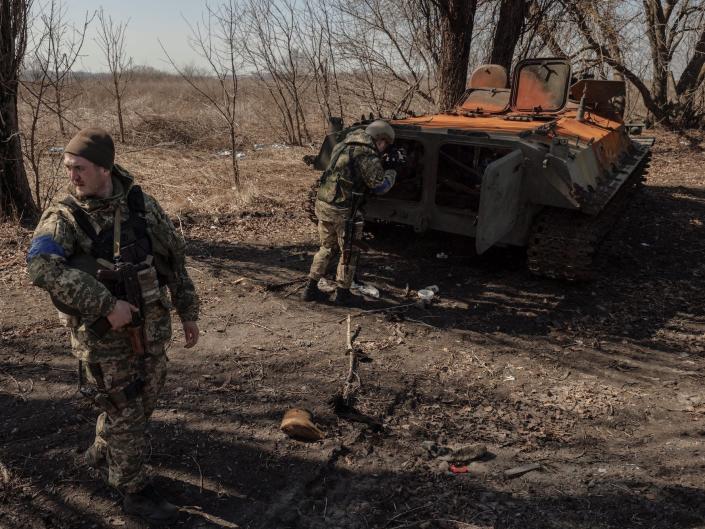 Ukraine soldier near wrecked Russian armored vehicle