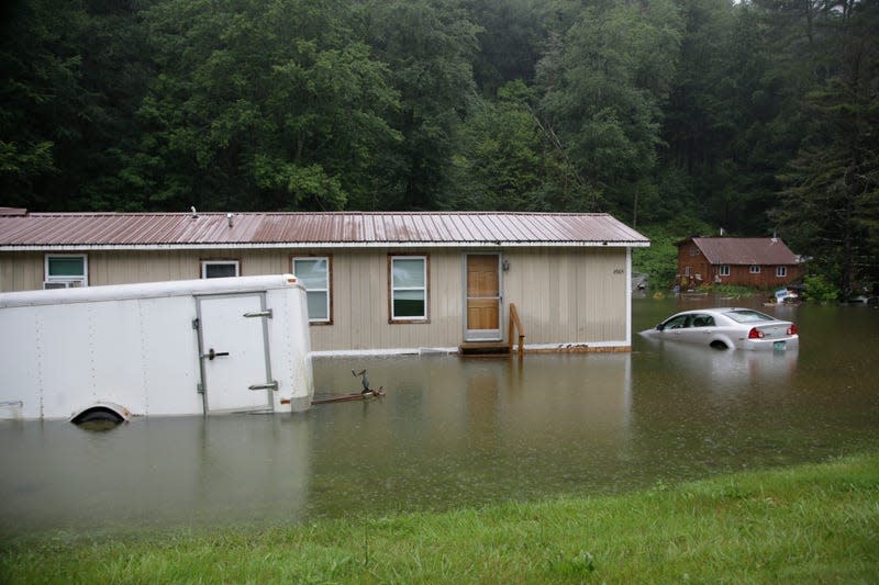 Floodwaters rise in Bridgewater, Vt., on Monday, July 10, 2023, submerging parked vehicles and threatening homes near the Ottauquechee River.