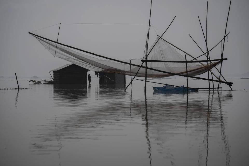 A villager holds her baby as she prepares to leave her submerged house in Sandahkhaiti, a floating island village in the Brahmaputra River in Morigaon district, Assam, India, Wednesday, Aug. 30, 2023. (AP Photo/Anupam Nath)