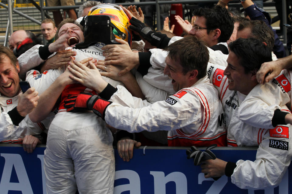 FILE - In this Sunday, April 17, 2011 file photo, McLaren Formula One driver Lewis Hamilton of Britain, with yellow helmet, celebrates with his crews after winning the Chinese Formula One Grand Prix in Shanghai, China. British driver Lewis Hamilton made Formula One history on Sunday, Oct. 25, 2020 winning the Portuguese Grand Prix for a 92nd win to move one ahead of German great Michael Schumacher. (AP Photo/Eugene Hoshiko, file)