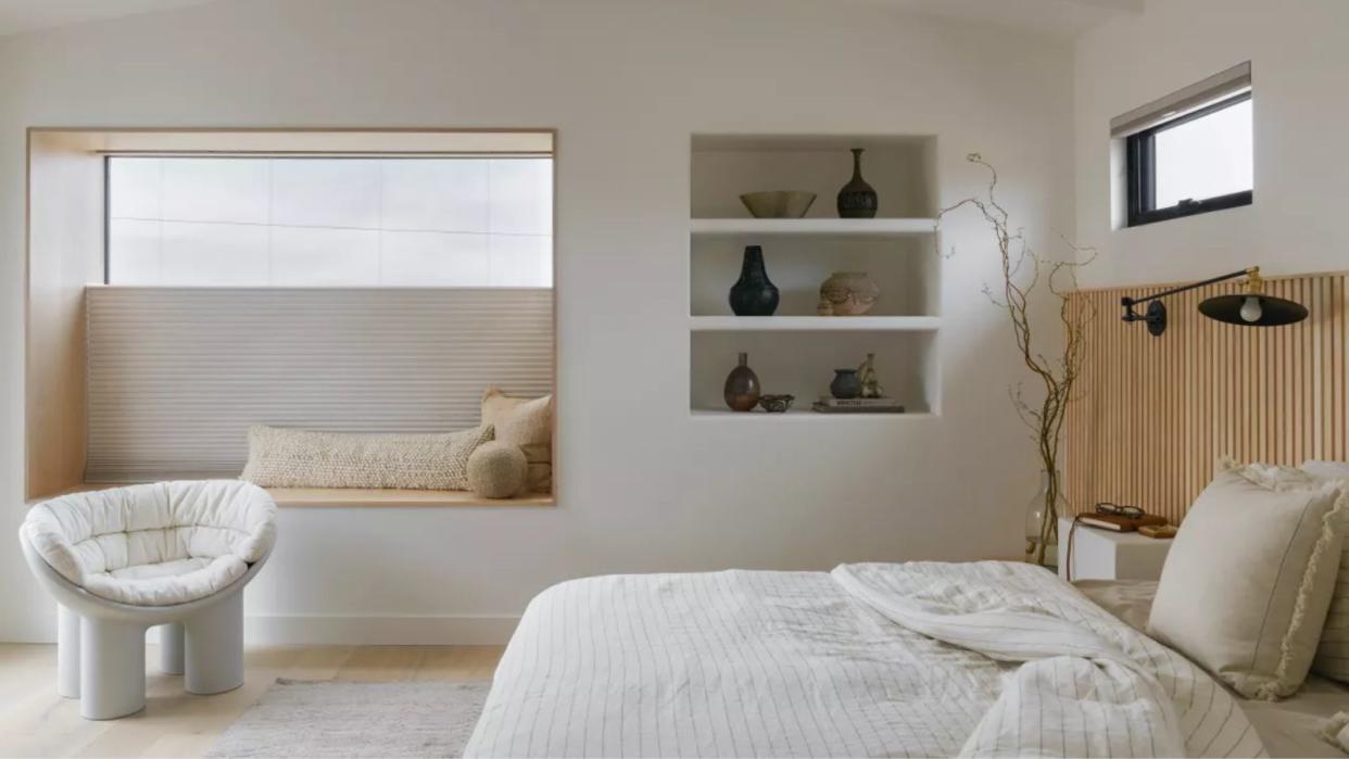  A minimalist bedroom with high windows, and a bed with white linens  