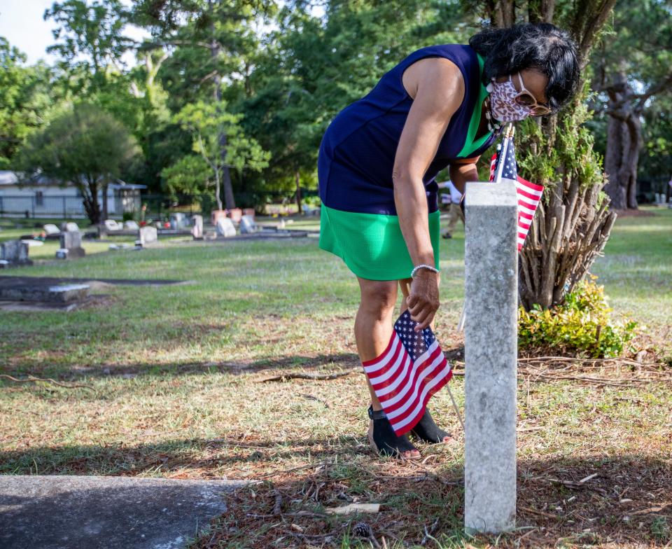 Commissioner Carolyn Cummings places an American flag next to a headstone in the Greenwood Cemetery on Memorial Day, May 31, 2021.