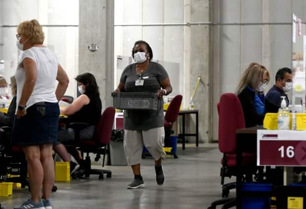 A special ballot officer carries ballots at Elections Canada's distribution centre in Ottawa on Monday. (Justin Tang/The Canadian Press - image credit)