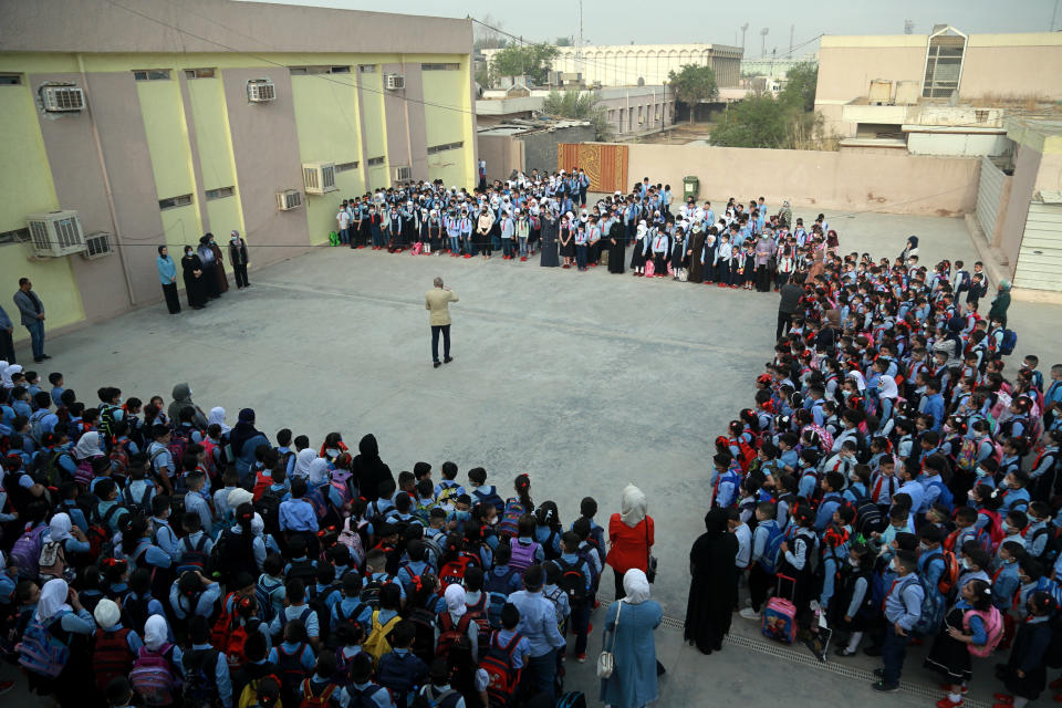 School students, wearing facemasks, gathered in the playground at the beginning of the school year in Baghdad, Iraq, Monday, Nov. 1, 2021. Across Iraq, students returned to classrooms Monday for the first time in a year and a half – a stoppage caused by the coronavirus pandemic - amid overcrowding and confusion about COVID-19 safety measures. (AP Photo/Hadi Mizban)