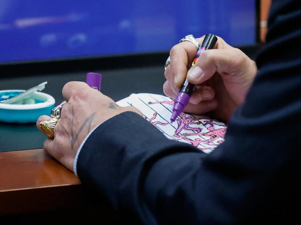 Depp’s sketching was captured by press photographers (POOL/AFP via Getty Images)