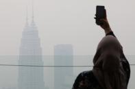 A tourist takes a picture of the city skyline shrouded by haze at Kuala Lumpur Tower in Kuala Lumpur