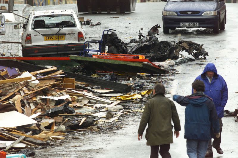 FILE PHOTO: Security experts examine the charred remains of the vehicle thought to have contained the bomb which exploded in Omagh's shopping area in Northern Ireland