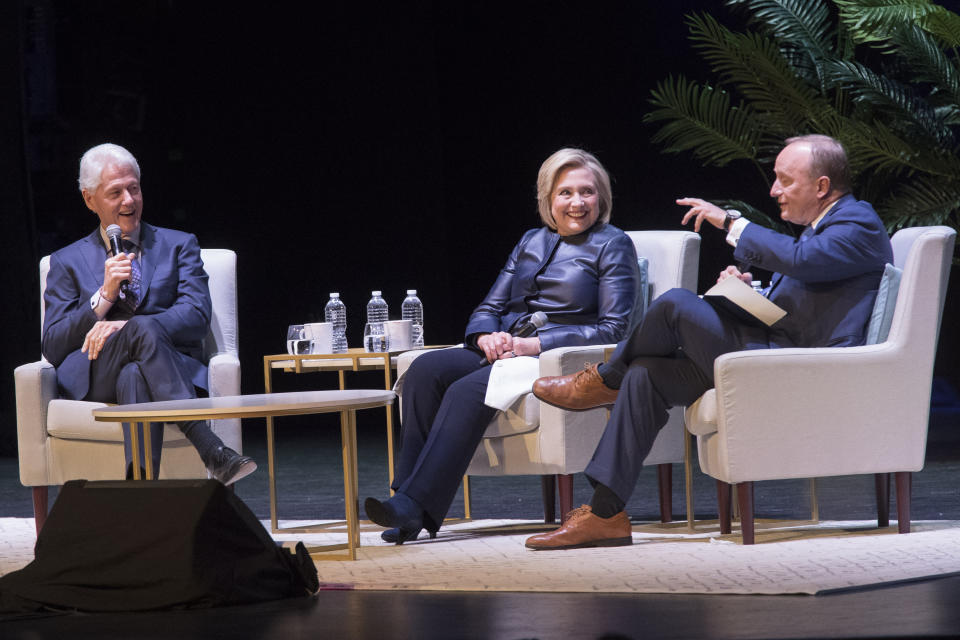 Former President Bill Clinton, left, and former Secretary of State Hillary Rodham Clinton, center, smile as Paul Begala speaks during "An Evening with the Clintons", Thursday, April 11, 2019, at the Beacon Theatre in New York. (AP Photo/Mary Altaffer)