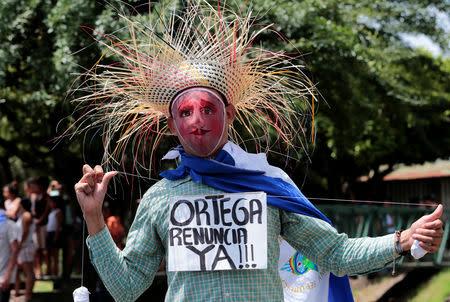A masked demonstrator holds a sign that reads "Ortega, quit now!" during a protest against Nicaraguan President Daniel Ortega's government in Managua, Nicaragua September 23, 2018. REUTERS/Oswaldo Rivas