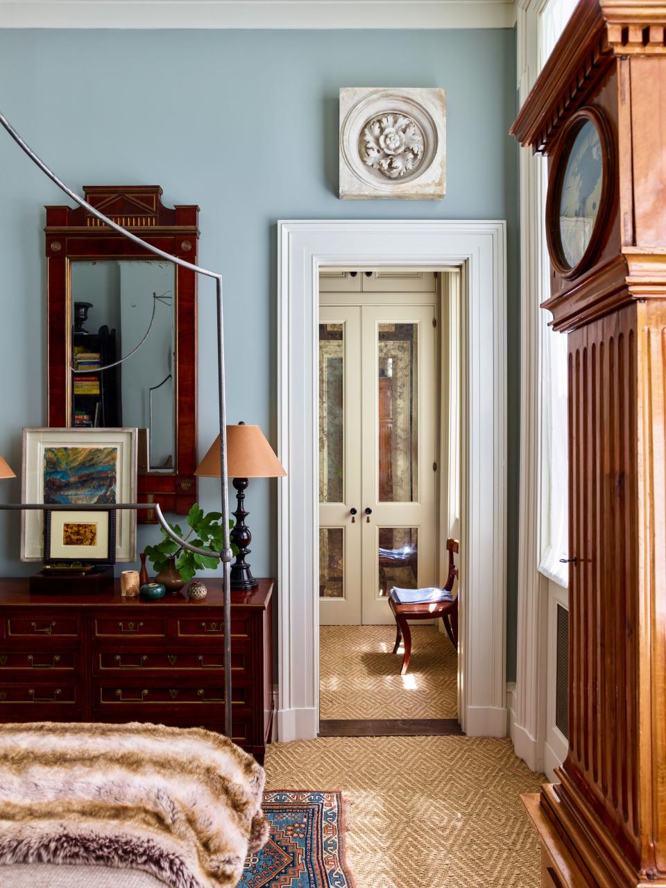“I love layers and things that tell a story,” says Schafer. “Anyone who’s in this business falls in love with objects to their own peril.” In the bedroom, which is painted in Farrow & Ball’s Light Blue, an antique carpet found in Maine sits atop sea-grass wall-to-wall carpeting by Patterson Flynn & Martin. The 1940s chest of drawers from Sutter Antiques is topped with a Russian mirror from Evergreen Antiques and a contemporary pastel landscape sketch from Charles Plante Fine Arts. A plaster ceiling medallion found at the Pier Antiques Show hangs above a doorframe leading to the dressing area.