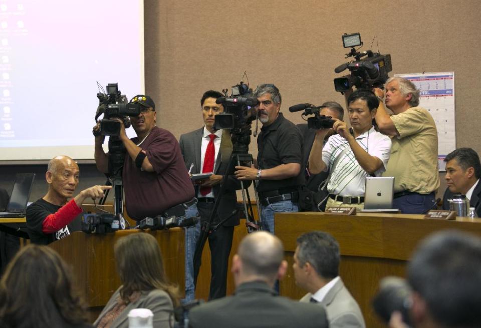 Sriracha hot sauce founder David Tran, at podium, left, addresses a city council meeting in Irwindale, Calif., Wednesday, April 23, 2014. The city of Irwindale is suing the maker of Sriracha hot sauce and last week the Los Angeles suburb tentatively voted to declare the bottling plant a public nuisance. Irwindale City Attorney Fred Galante says relocating seems extreme and the city only wants to see the smell issue addressed. (AP Photo/Damian Dovarganes)