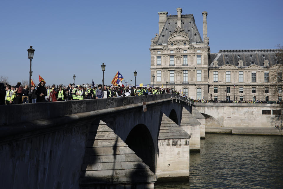 Yellow vest protesters cross the Seine river on the Royal bridge while demonstrating in the streets of Paris, France, Saturday, Feb. 23, 2019. French yellow vest protest organizers are trying to tamp down violence and anti-Semitism in the movement's ranks as they launch a 15th straight weekend of demonstrations. (AP Photo/Kamil Zihnioglu)